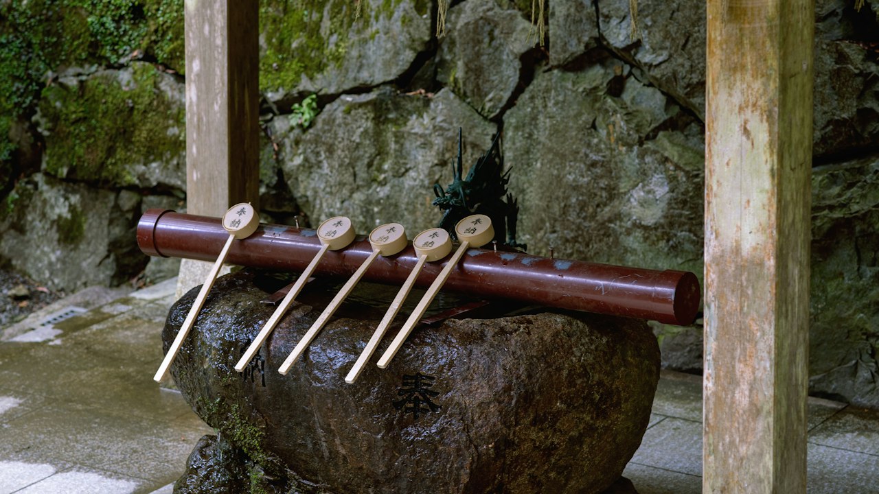 Wooden ladles rest on a stone basin near a wall