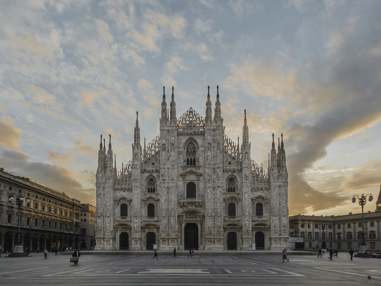 The Duomo di Milano cathedral in Milan under a soft orange and blue sky