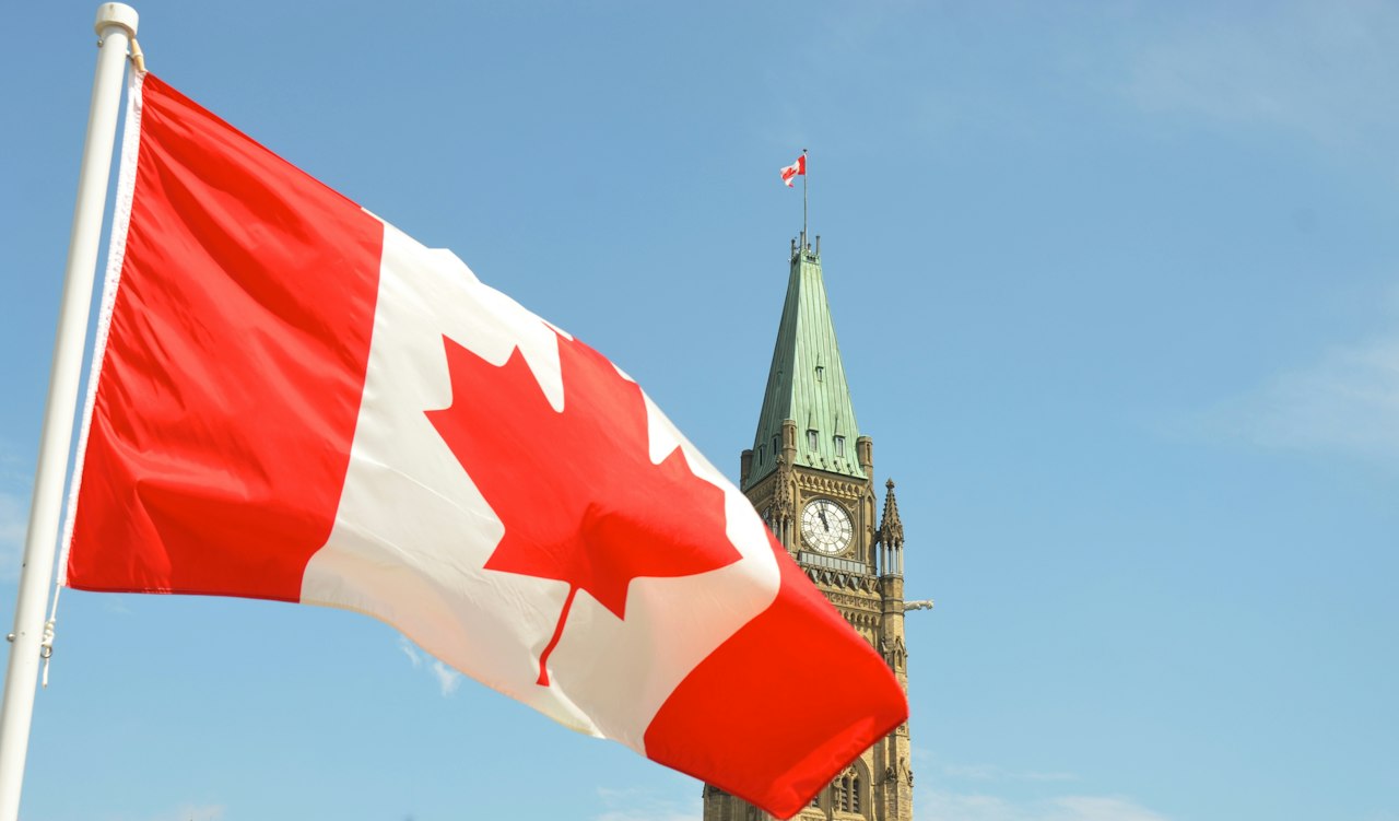 A Canadian flag waving before the Peace Tower on Parliament Hill in Ottawa