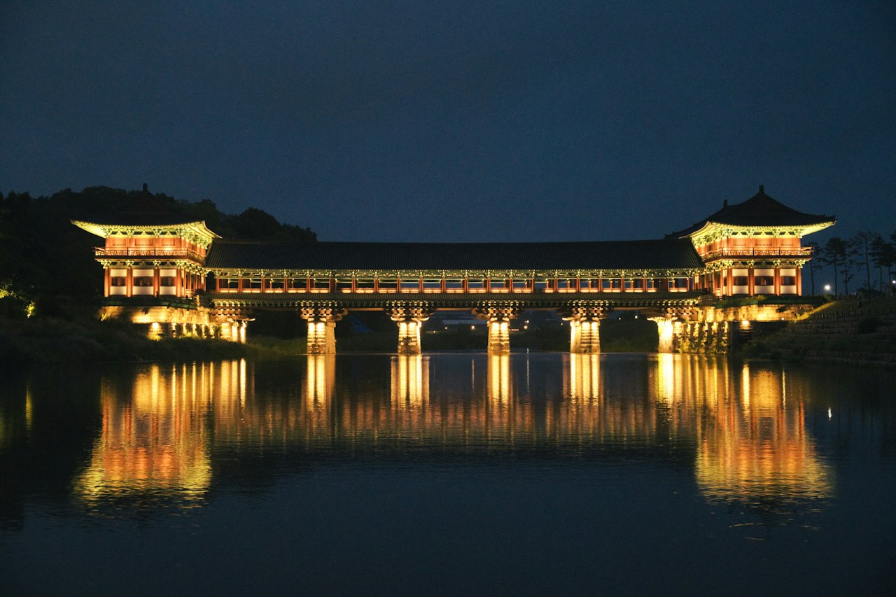 Traditional asian bridge illuminated at night reflecting in calm water