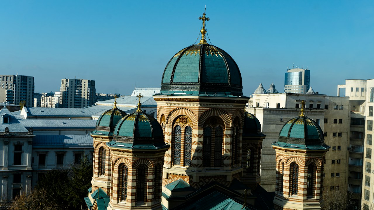 The green domes of the Kretzulescu Church in Bucharest surrounded by city buildings