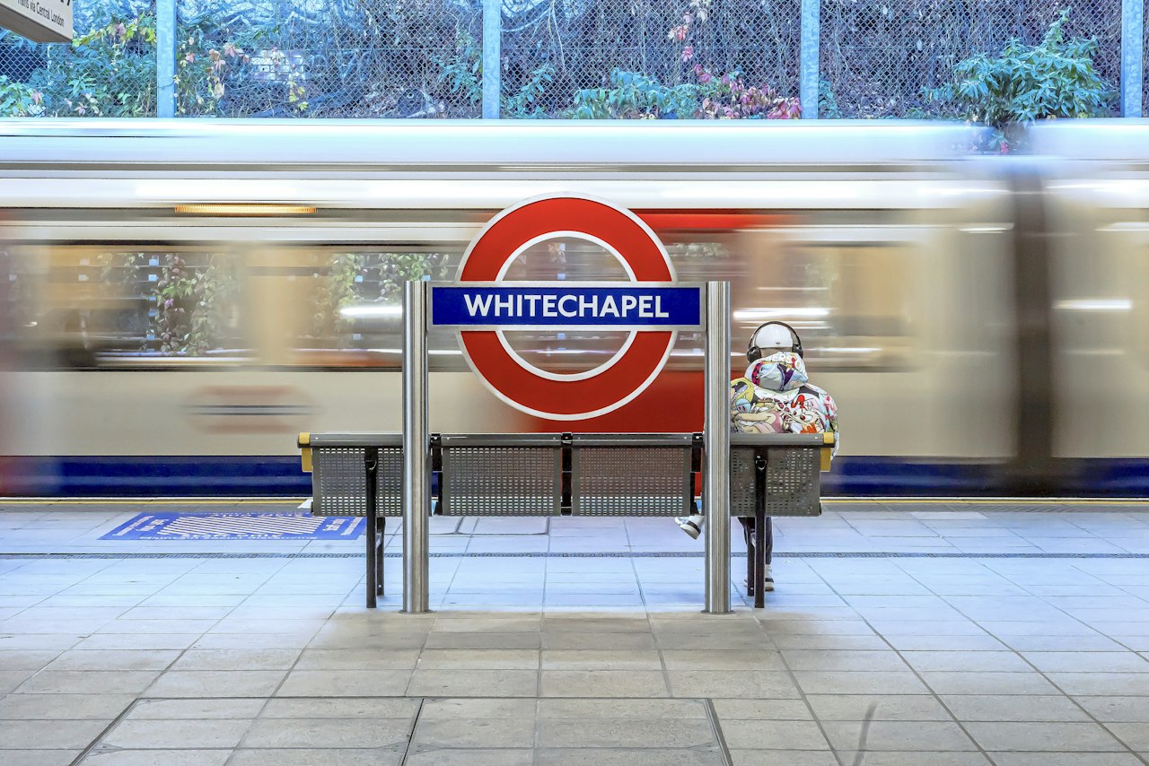 a person sitting on a bench in front of a train