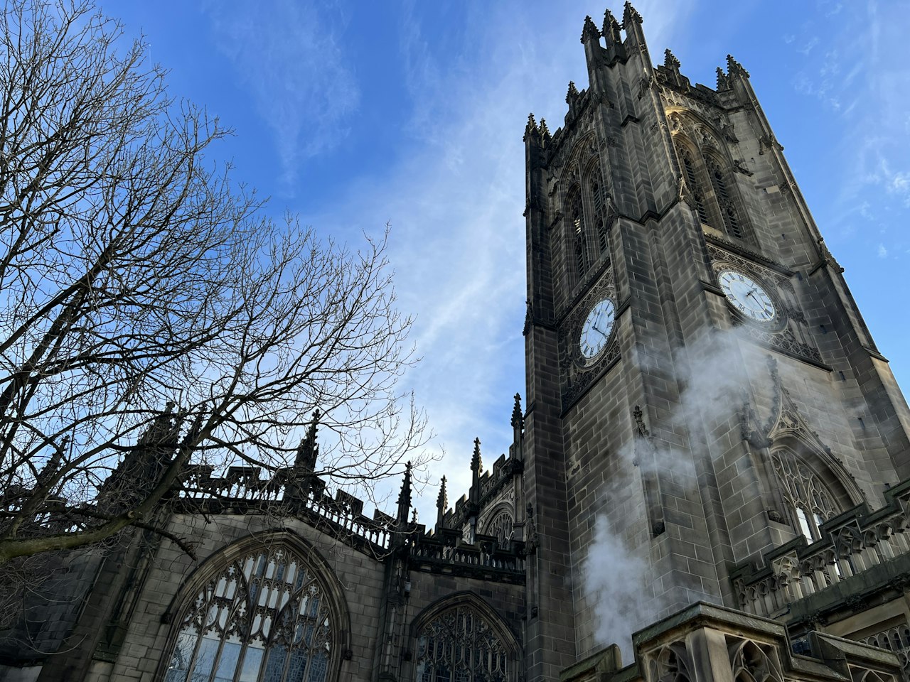 Historic stone church with clock tower and bare trees